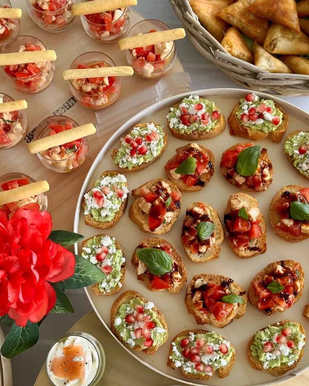 Plateau de bouchées apéritives : bruschettas à l'avocat et à la grenade, tartines tomate-basilic, verrines et samoussas