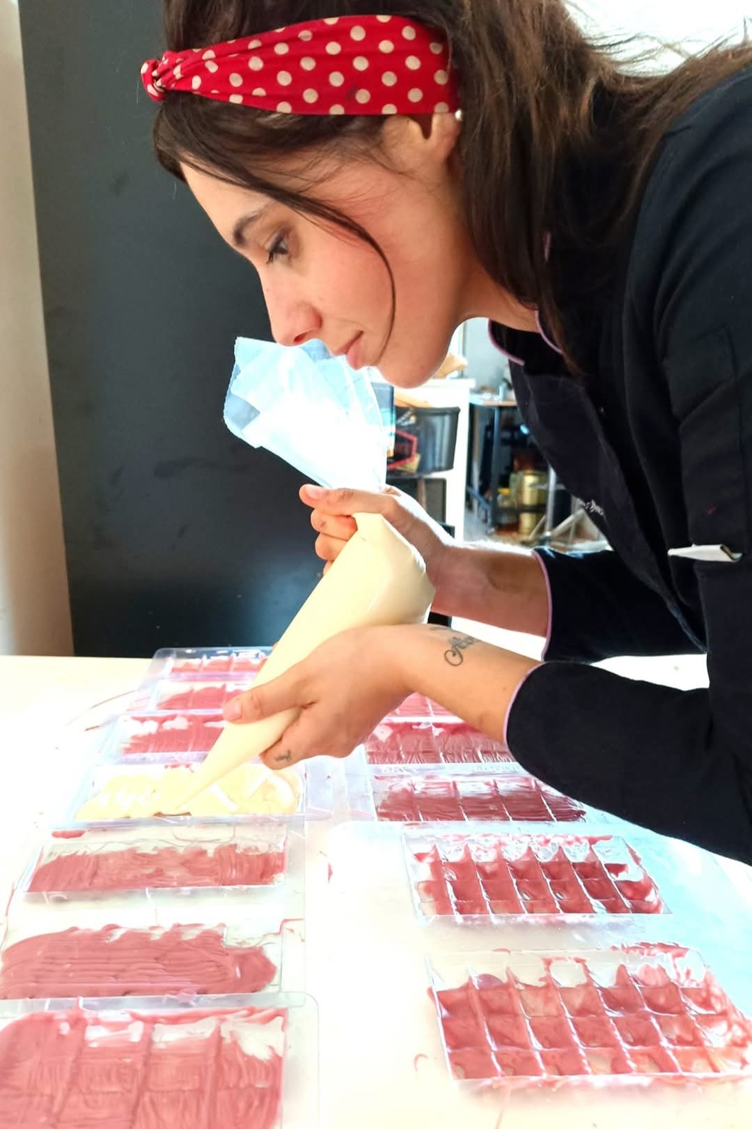 Océane garnit à la poche à douille des moules à tablettes de chocolat rose